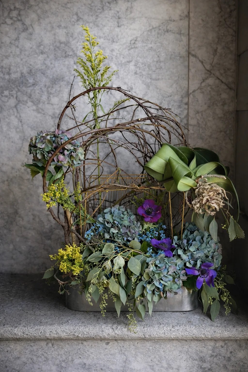 Sculptural hydrangea and anemone arrangement with vine birdcage