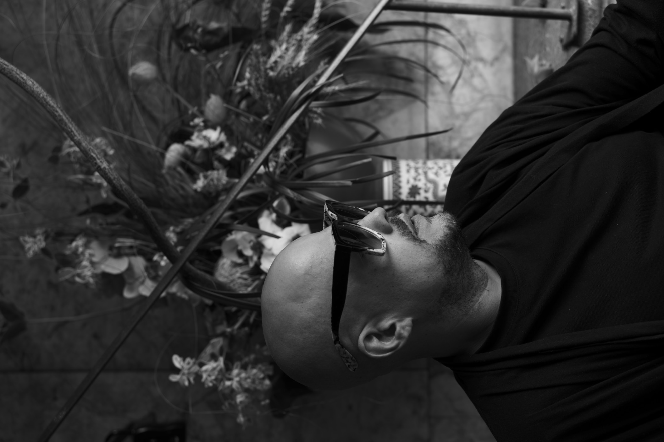 Brandon Joseph, founder and florist of Lovely Coven, seated beneath a sculptural floral installation