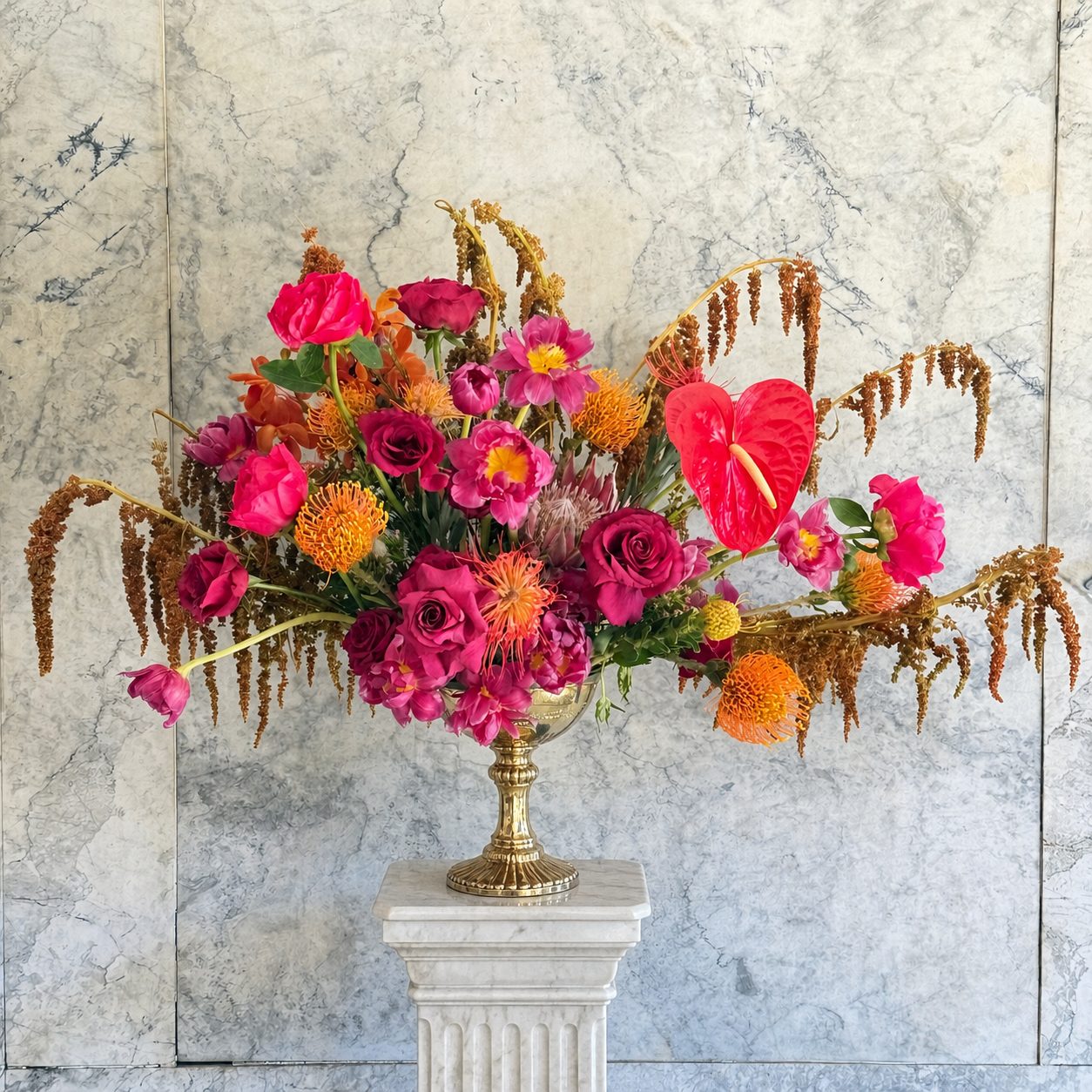 Fuchsia tropical arrangement with anthurium against marble wall