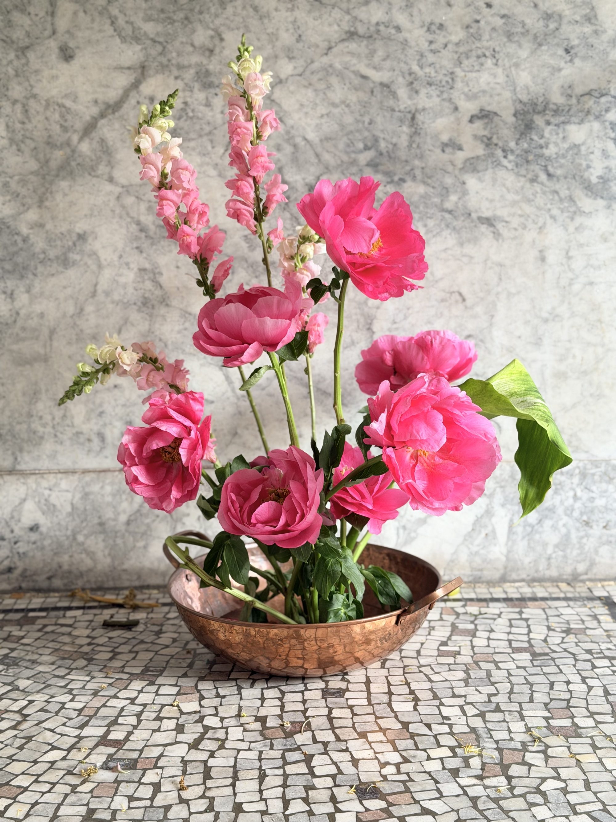 Pink peonies in copper bowl on marble surface