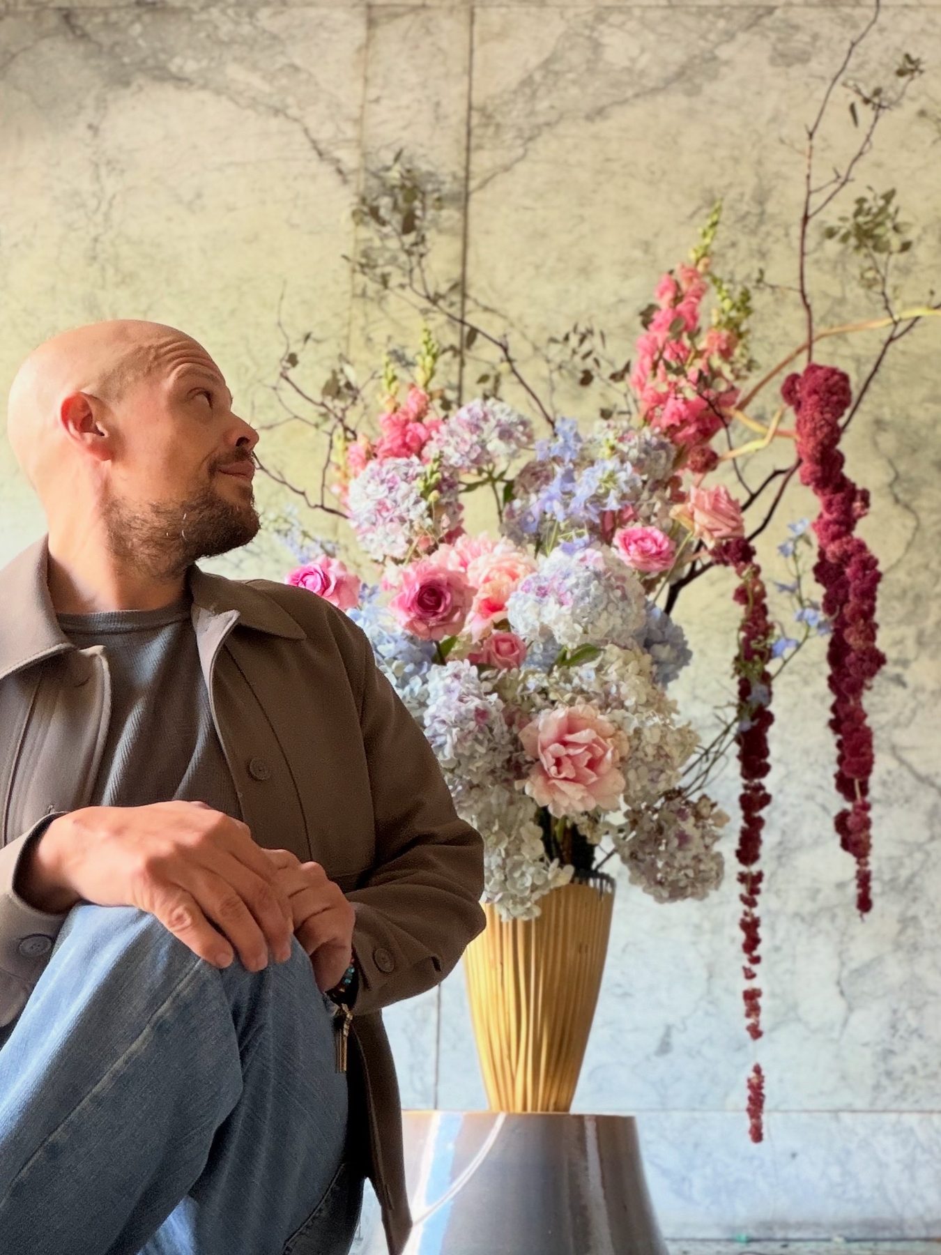 A floral portrait with a watchful sculpted face emerging beneath its blooms