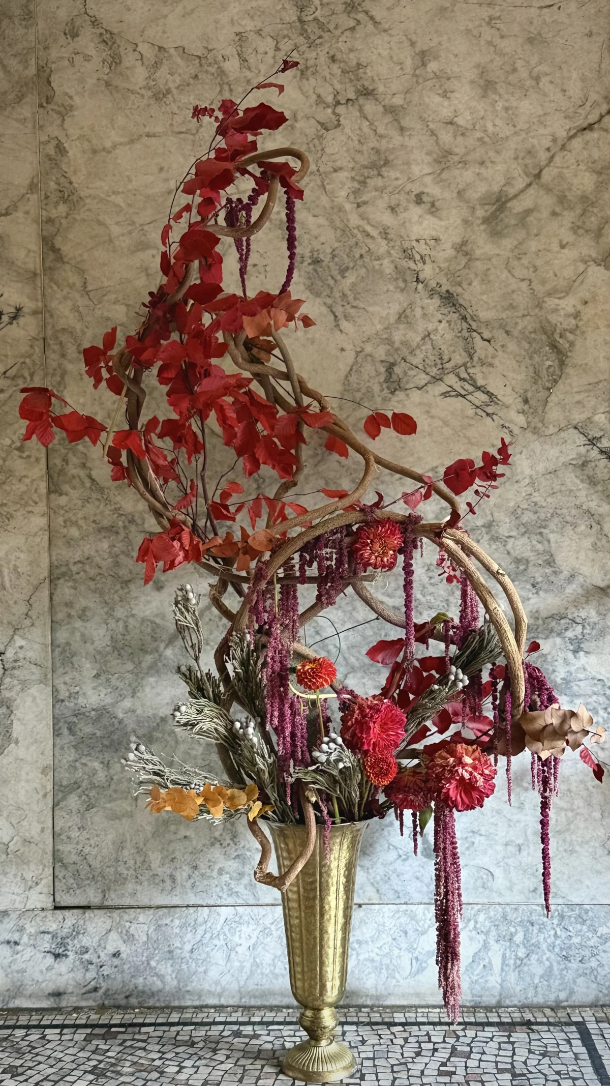 Twisting heirloom wisteria vine with scarlet bougainvillea, burgundy amaranthus, crimson dahlias and silver brunia in an antique brass urn